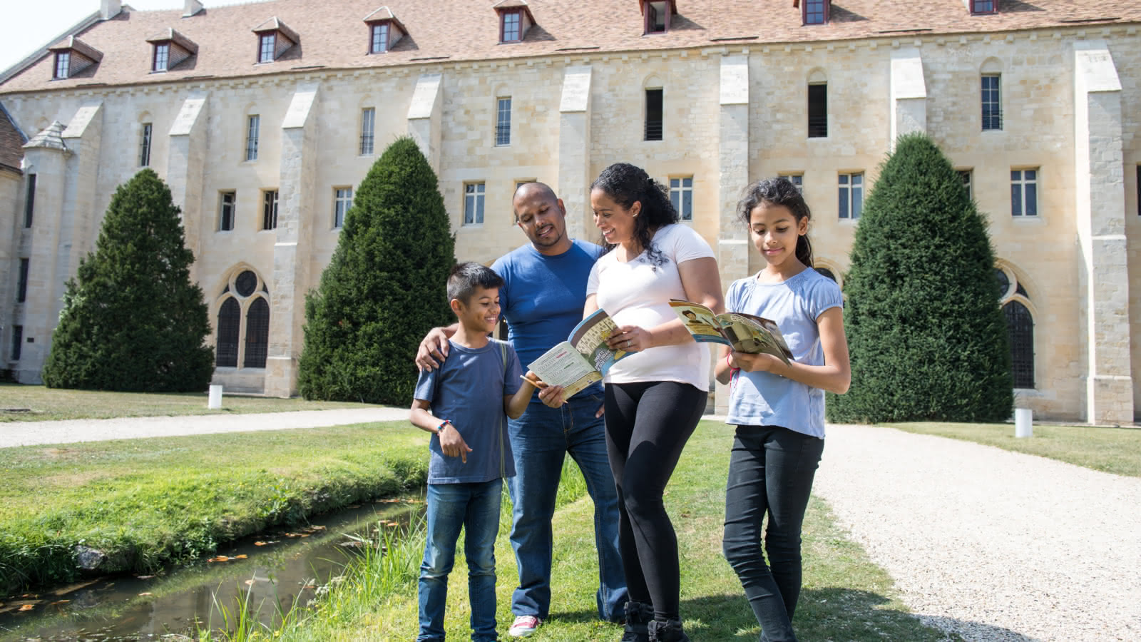 Photo d'une famille avec des livrets de jeux-parcours devant l'Abbaye de Royaumont